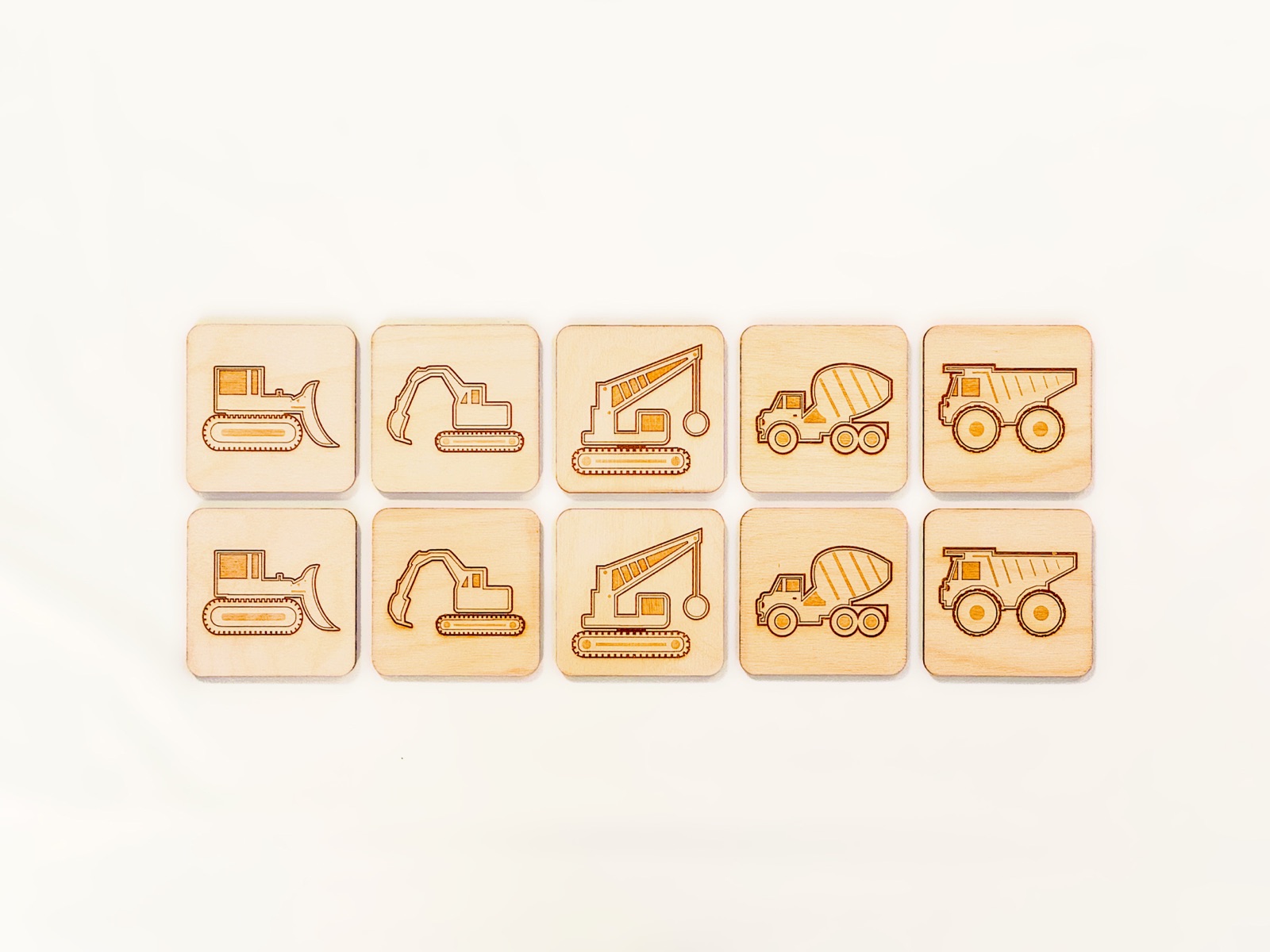 Ten wooden construction vehicle memory match tiles laid out flat
