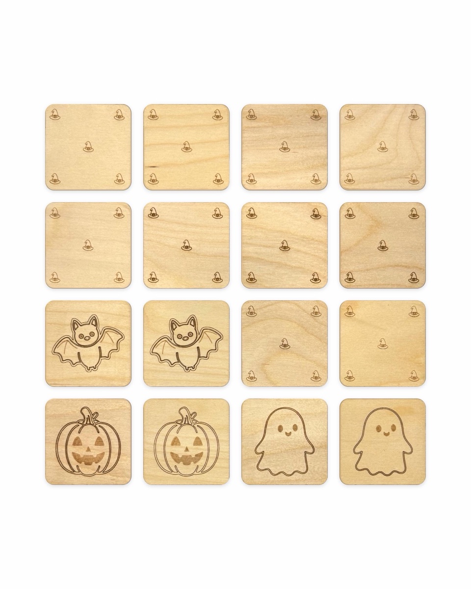 A memory match game in progress in a four by four grid: ten Baltic birch tiles face down showing small engraved witch hats, and six face up as three found pairs of bats, jack-o'-lanterns, and ghosts
