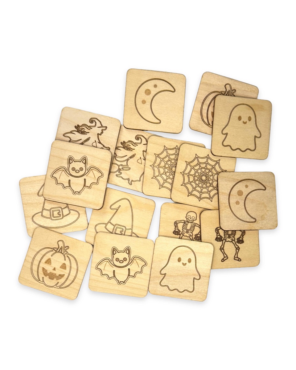 Sixteen engraved Halloween tiles in a loose overlapping pile on white, with moons, ghosts, bats, jack-o'-lanterns, witch hats, skeletons, spider webs, and witches all facing up