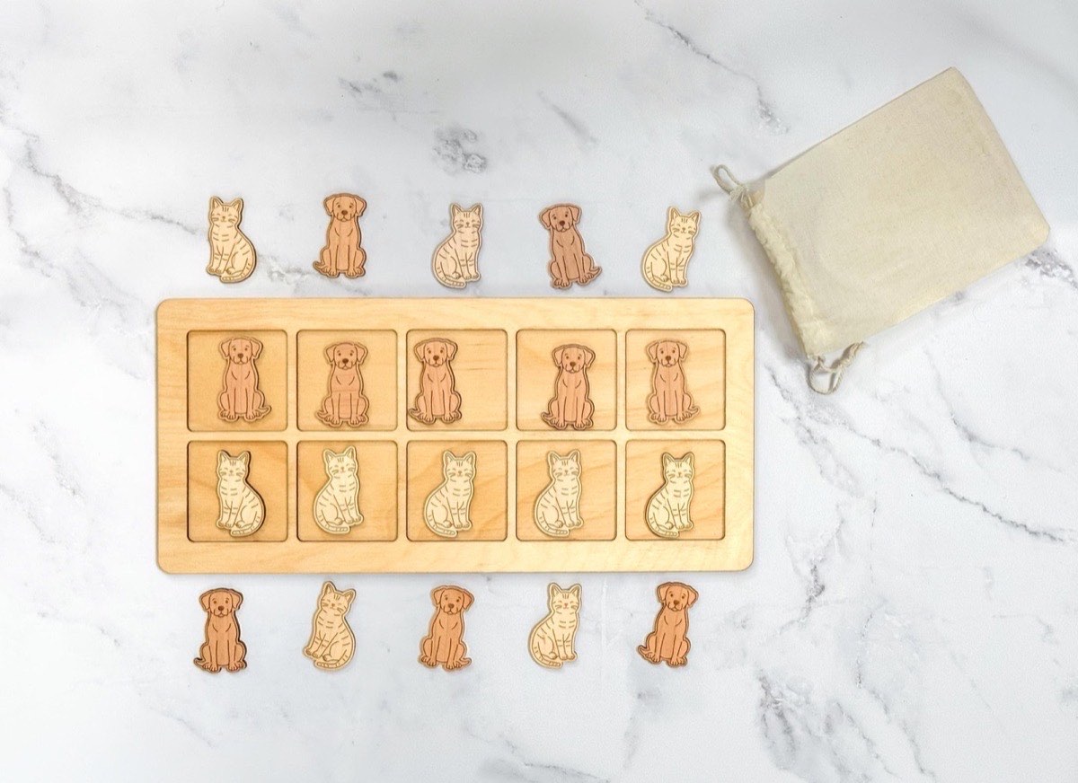 Cats and dogs ten frame set spread on white marble with a natural muslin drawstring bag, ten counters filling the personalized board and ten extra wooden pieces arranged around it